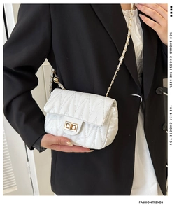 White quilted saddle bag with gold hardware worn over a black blazer for high contrast