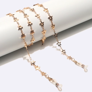 Golden star-shaped link eyewear chain with silicone loops on a white prop pedestal