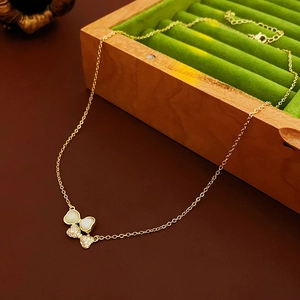 Détail du pendentif papillon doré avec nacre et cristaux sur un écrin en velours vert
