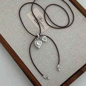 French vintage heart pendant necklace with rhinestones and brown cord on a display board