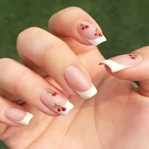 Close-up of square French manicure press-on nails with natural pink base and cherry detail