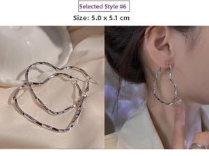 Detail of silver twisted heart drop earrings with size 5.0x5.1cm on a model and shell decor