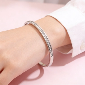 Macro shot of silver titanium bangle with paved pavé zircons worn on female wrist