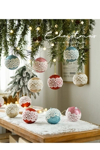 Close-up of 8cm glitter Christmas balls with lace finish hanging on a festive pine branch