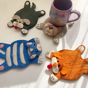 Detailed view of four handmade wool felt coasters with cute cartoon animal designs