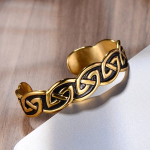 Detail of vintage gold-tone Viking bracelet featuring black enamel Celtic knot texture