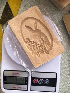Macro detail of a carved wooden cookie mold featuring a rabbit and rose floral pattern