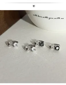 Close-up of 925 sterling silver ear clips with four-prong set black and white zircons