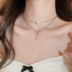 Detail of layered silver necklace featuring a butterfly zircon pendant and a white pearl