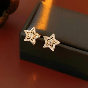 Close-up of gold star earrings featuring micro-paved cubic zirconia stones and metal finish