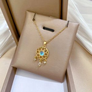 Macro detail of golden dreamcatcher necklace pendant with blue gemstone in a gift box