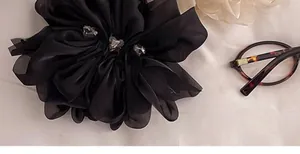 Große schwarze Chiffon-Blumen-Haarklammer mit herzförmigen Akzenten in Nahaufnahme