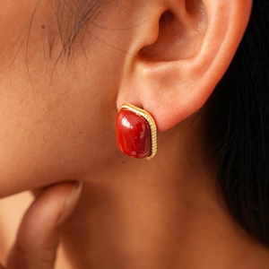 Gros plan d'un mannequin portant une boucle d'oreille vintage en or et pierre rouge