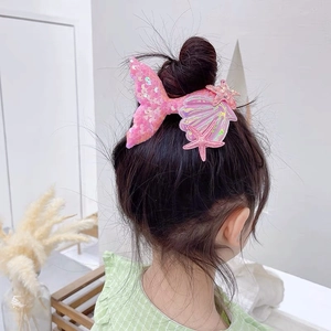 Detail showing pink sequin mermaid tail and seashell hair clips on a girl's hairstyle