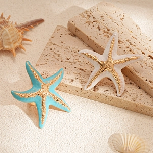 Starfish enamel ring set in blue and cream white with gold textures on sandy stones