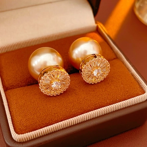 Macro detail of gold-plated pearl drop earrings with zircon floral studs on velvet