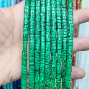 Close-up of natural malachite beads with vibrant green stripes in cylindrical shape
