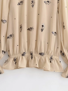 Détail de broderie de sequins floraux sur chemisier en mousseline beige et taille