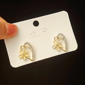 Detail of flower heart earring featuring cat eye petals, crystals and a small pearl