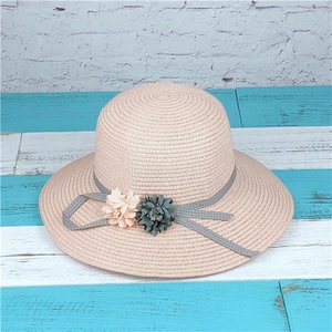 Detail of pink straw sun hat featuring a polka dot bow and delicate floral accents