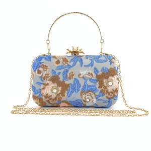 Close-up of floral embroidery and pearl beadwork on a luxury evening clutch bag