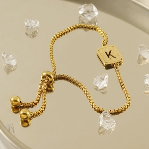 Close-up of gold titanium steel bracelet with letter K pendant and adjustable slider clasp