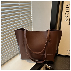 Detail view of large brown faux leather tote bag with dual straps in a lifestyle setting