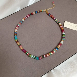 Macro view of multi-color disk beads necklace with gold metal chain and teardrop pendant