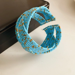 Détail d'un bracelet jonc ouvert multicouche tissé en perles de verre bleues et dorées