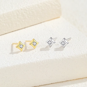 Elegant gold and silver star stud earrings with clear zircon stones on stone background
