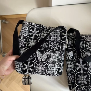 Close-up of white butterfly embroidery and geometric patterns on black canvas bag
