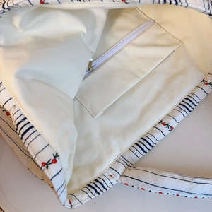 Vue interne montrant la poche zippée et la doublure matelassée fleurie du grand sac fourre-tout