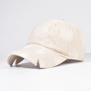Close-up of distressed cream baseball cap featuring vintage frayed details and worn texture
