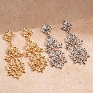 Orecchini pendenti vintage a fiori in oro e argento su sfondo di marmo