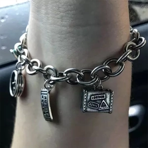 Close-up of travel-themed charm bracelet with suitcase and compass charms on wrist