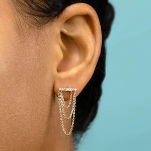 Elegant gold drop earrings with tiered tassel chains and crystal stones on blue background