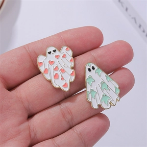 Cute Halloween ghost enamel pins in white and gold finish held on a person's palm