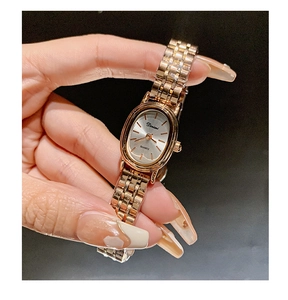Close-up of elegant gold steel strap watch with oval silver dial held in hand