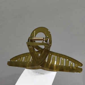 Detail showing an olive green resin hair claw clip with gold spring and Made in Korea tag