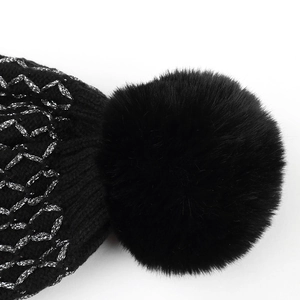 Close-up of black knit beanie with silver glitter thread patterns and a fluffy faux fur pompom