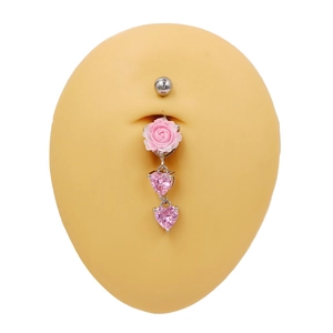 Détail du piercing de nombril argenté avec rose rose et gemmes en forme de cœur rose