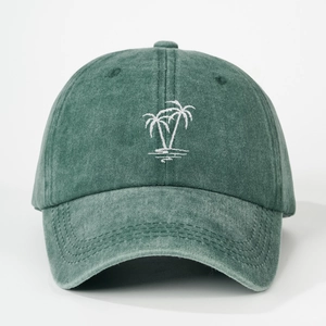 Close-up of embroidered white palm tree on washed green cotton baseball cap with curved brim