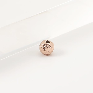 Macro shot of rose gold hammered stainless steel beads with pass-through holes for DIY jewelry