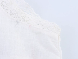 Detailed close-up of white lace embroidery and cotton linen fabric texture on French style set