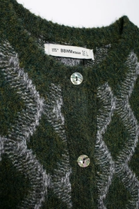 Vue détaillée du gilet tricoté vintage à losanges avec bouton perlé et étiquette de marque