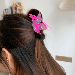 Detailed side view of a cute pink dinosaur acetate hair claw clip worn on hair
