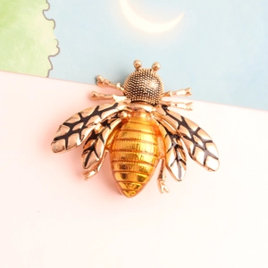 Detailed view of a golden bee brooch with black enamel stripes and rhinestone accents