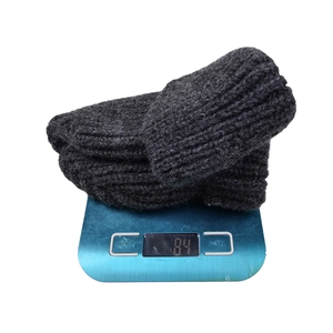 Close-up of dark grey thick ribbed knit beanie weighing 84g on digital scale