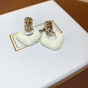 Detail of cream enamel geometric earrings with golden honeycomb textured metal studs