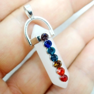 Chakra hanger van zeshoekig kristal met zilveren sluiting gepresenteerd in de hand